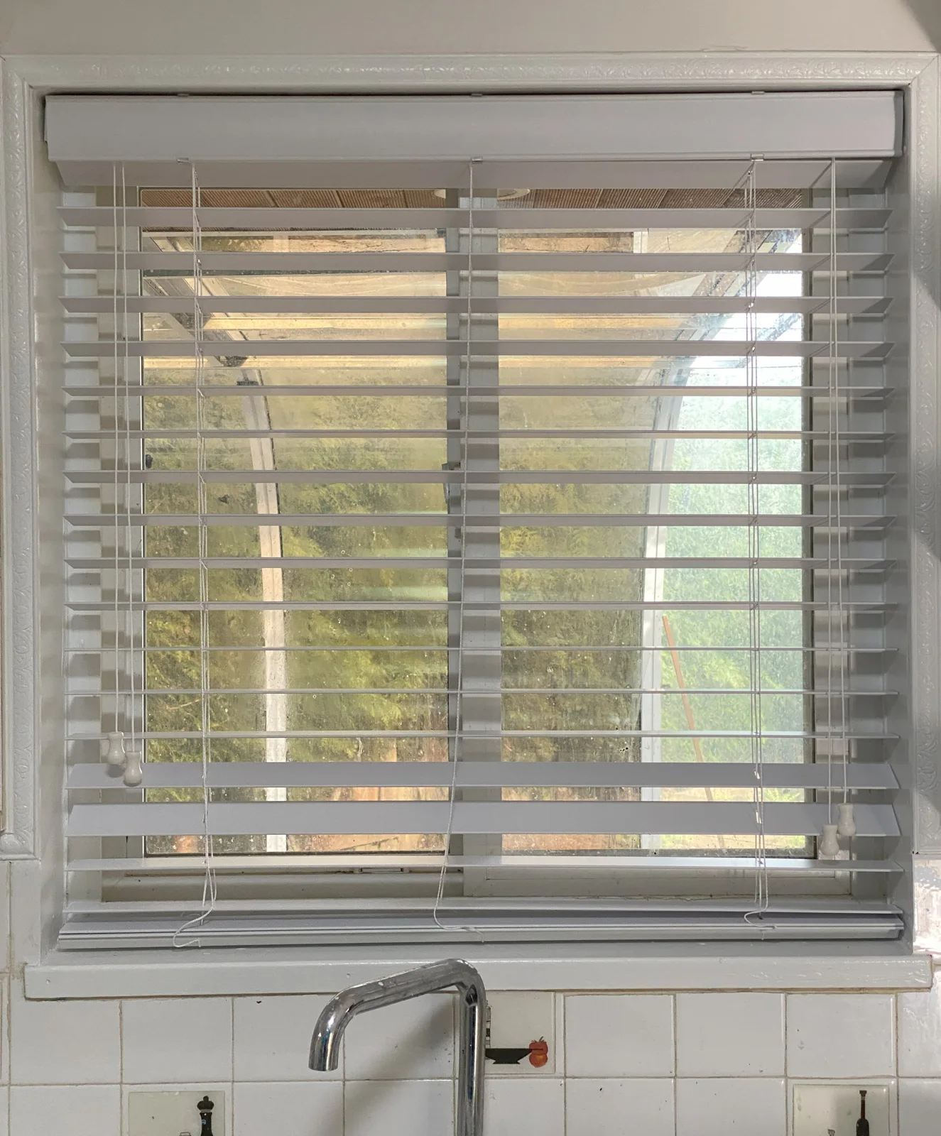 Faux wood blinds above a kitchen sink